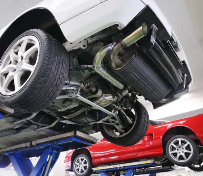 Lifted cars exposing undercarriage and exhaust